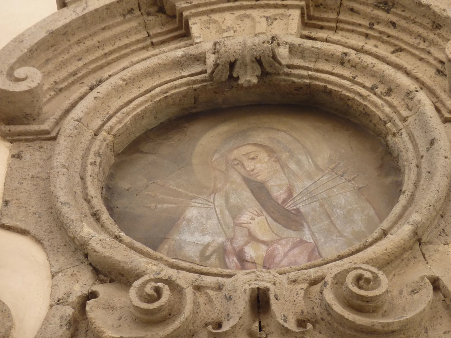 El fresco de la Virgen de los Dolores en el frontón partido sobre la portada