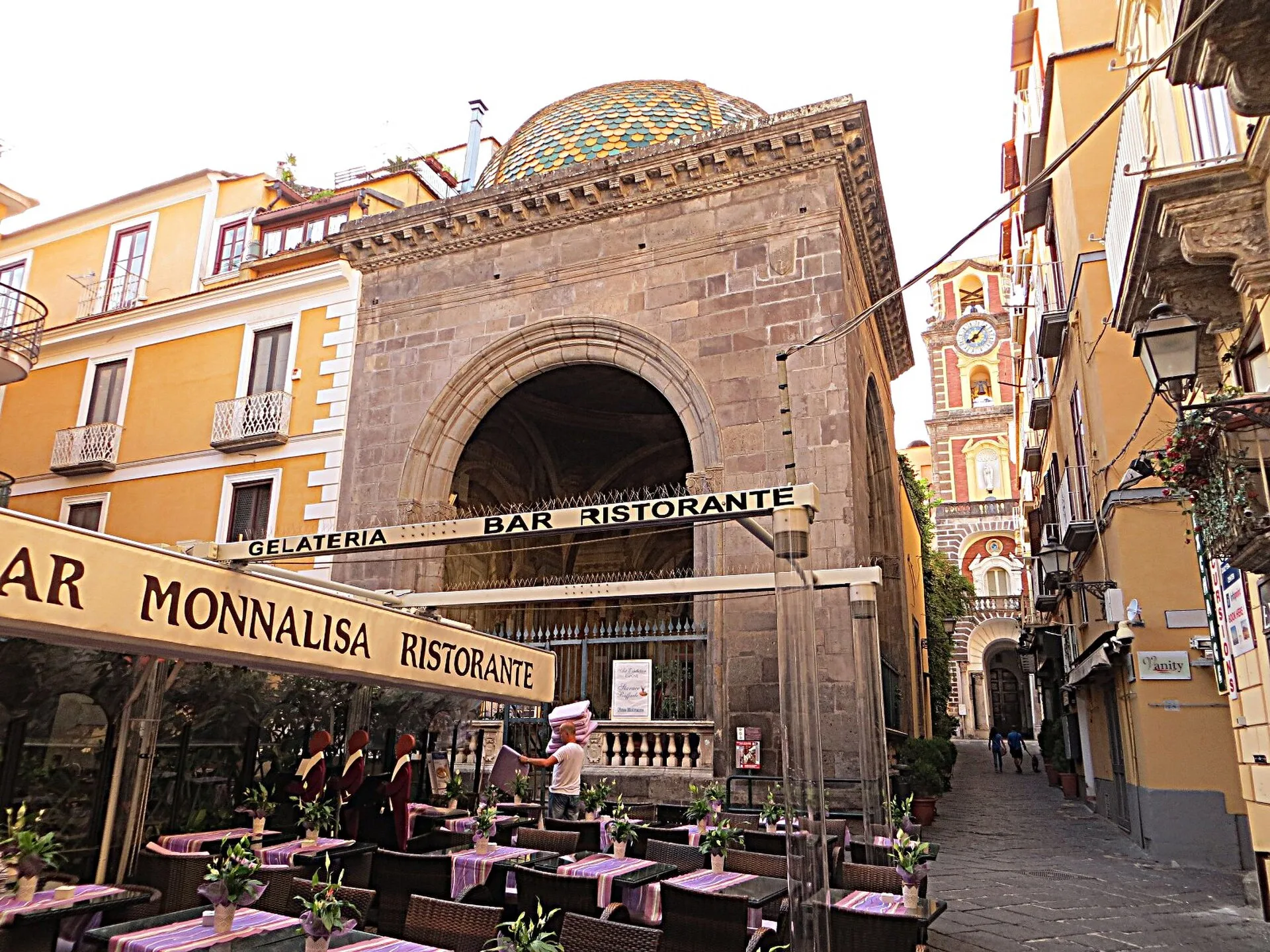 The Sedil Dominova and its majolica dome on Via San Cesareo, with the Cathedral bell tower behind