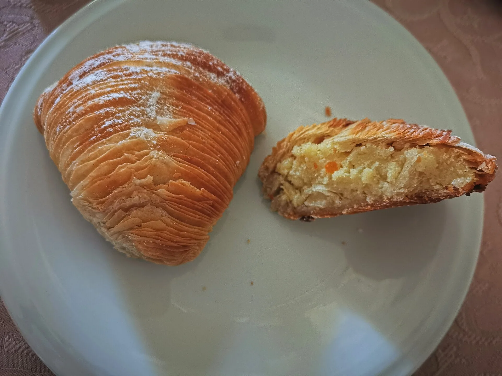 Sfogliatella riccia intera e aperta a metà, con il suo ripieno